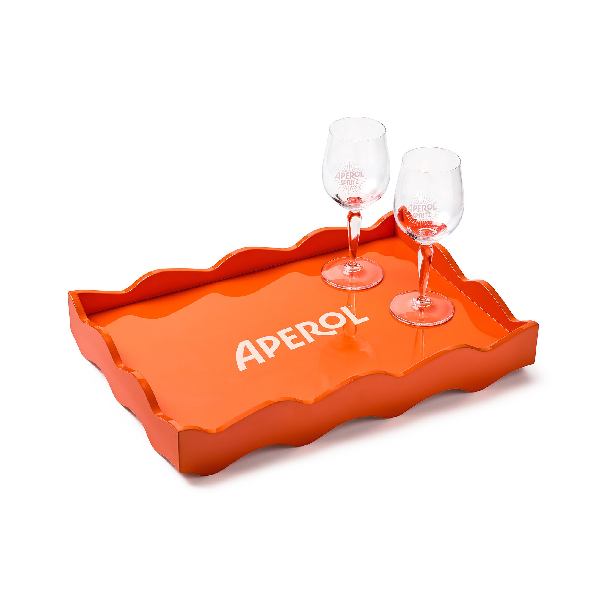 An orange wavy-edge serving tray with the word 'APEROL' printed in white on the bottom, shown on a white background with two clear stemmed glasses placed on top.