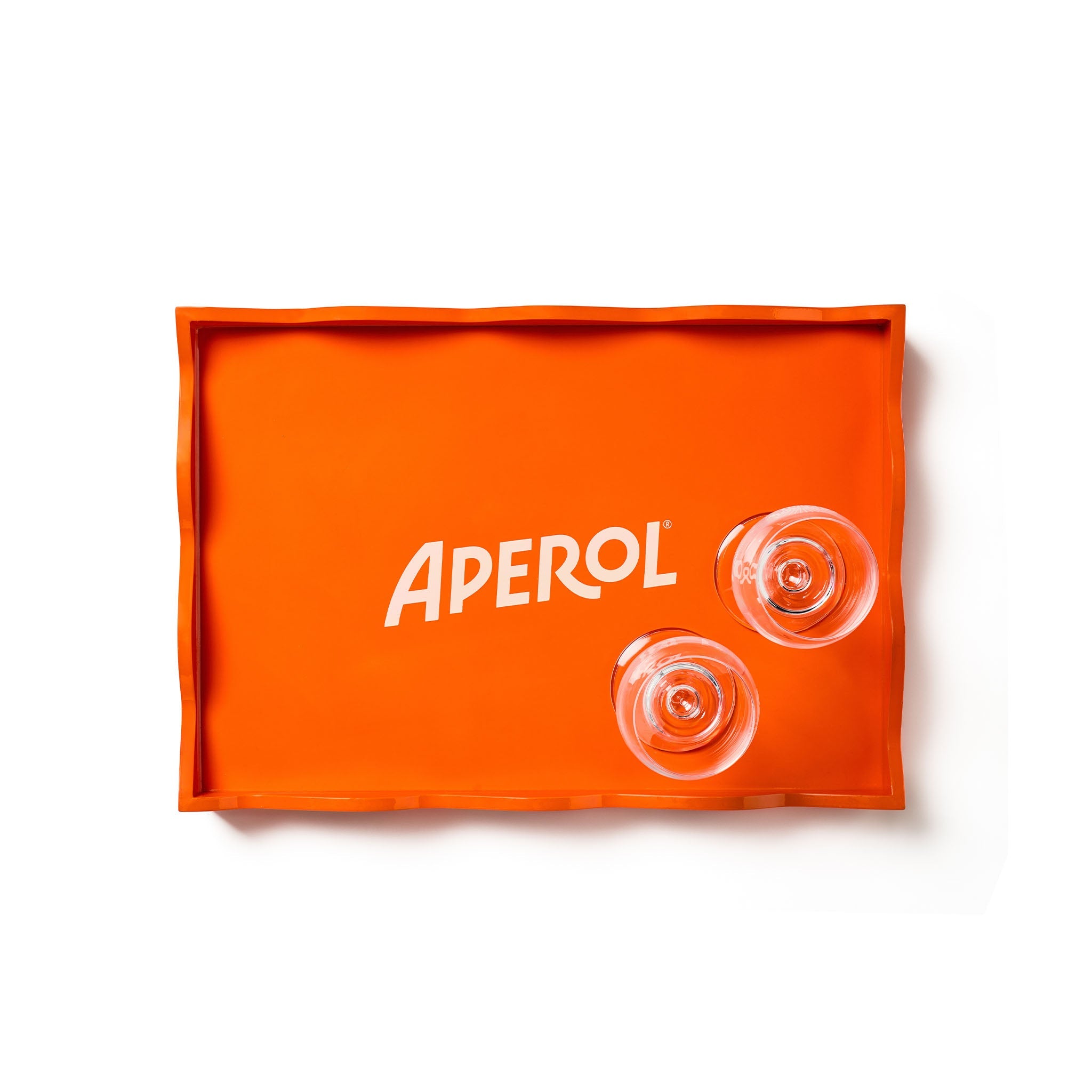An orange rectangular tray with a wavy rim, featuring the brand name 'APEROL' in white text and two Aperol glasses resting on its surface, set against a plain white background.